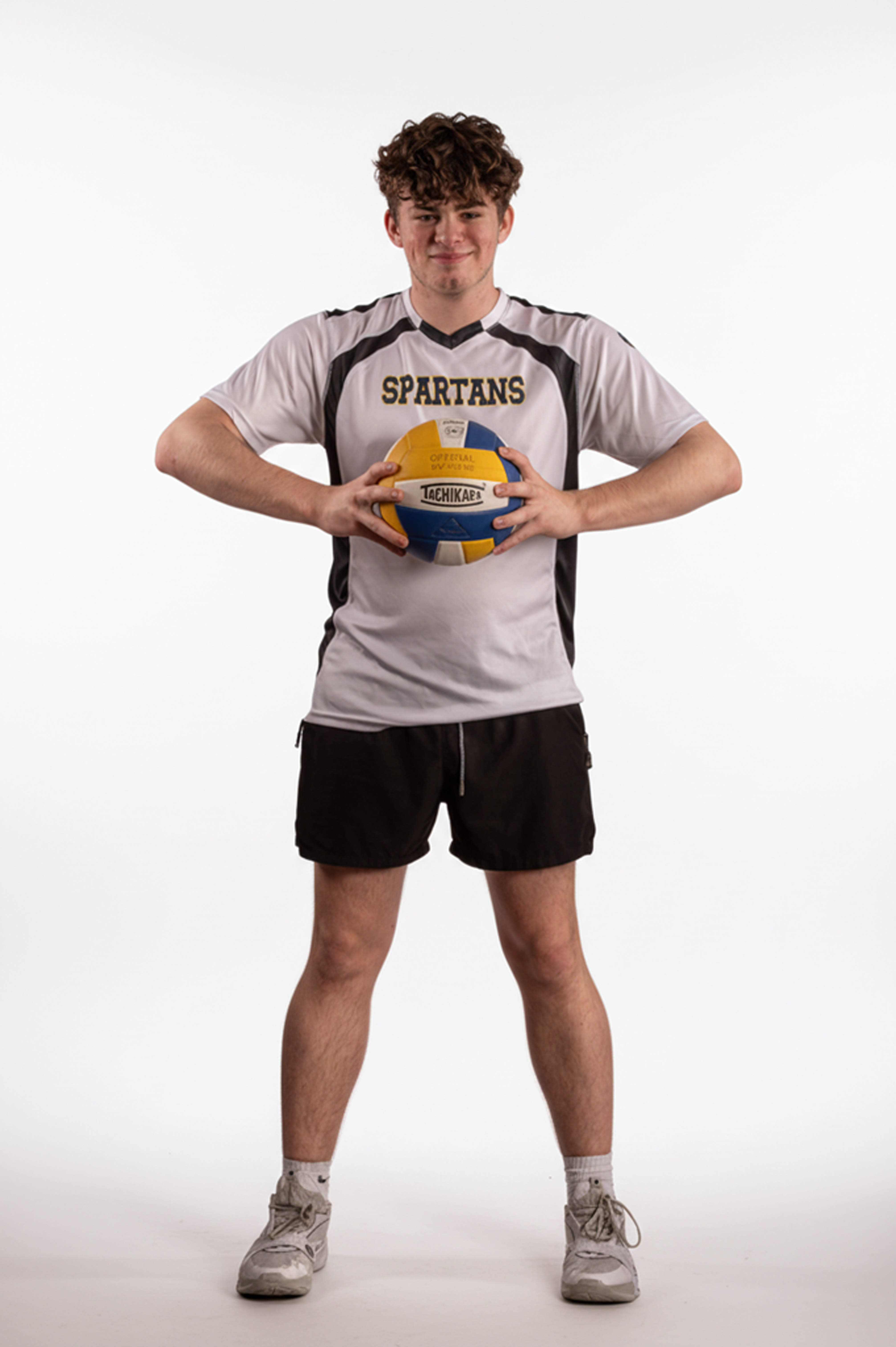Volleyball player posing with a volleyball on a white backdrop